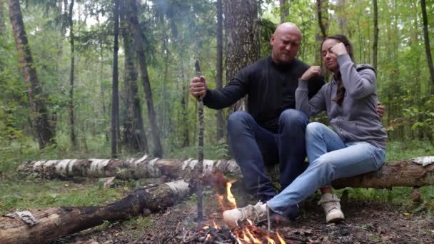 Um casal feliz adulto está acampando na floresta. Uma família de um homem e uma mulher estão sentados na floresta. — Vídeo de Stock