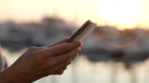 Detailní záběr ženských rukou odesílajících textovou zprávu do mobilního telefonu venku na rozmazaném pozadí, bočním pohledu, sledovacím snímku — Stock video