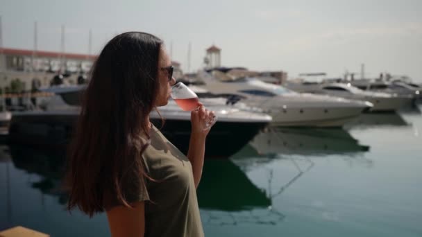 En framgångsrik kvinna njuter av ett glas champagne på bakgrunden av en yacht på en annan semester — Stockvideo