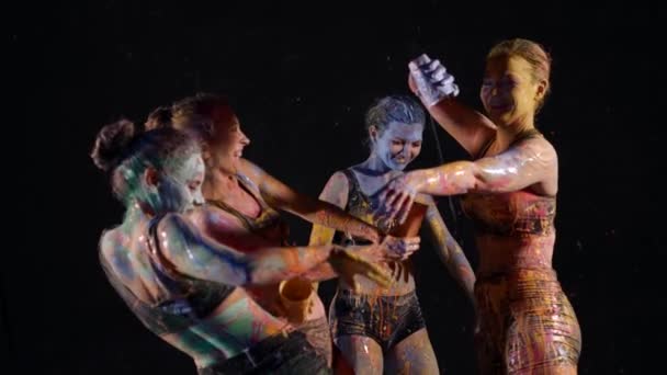 Quatro mulheres pulverizam-se com tinta multi-colorida e se divertem — Vídeo de Stock