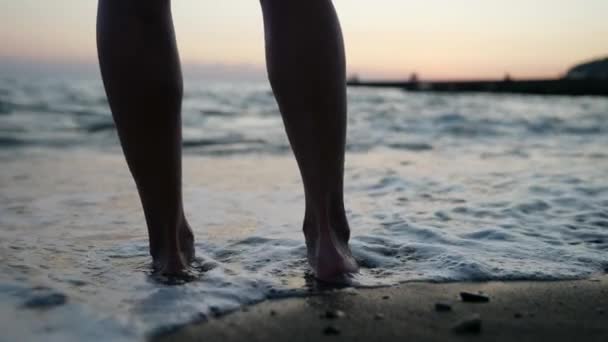 日没時に海岸に立つ優雅な女性の足のクローズアップ — ストック動画