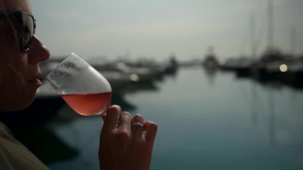 Close-up dari segelas sampanye merah muda di tangan seorang wanita sukses di resor pantai — Stok Video