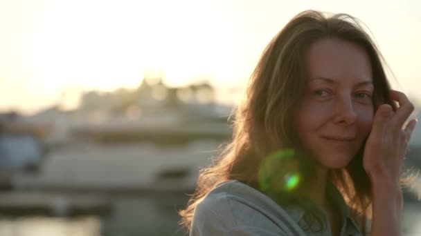 Portrait of a female tourist posing at the sea embankment the rays of the setting sun illuminate — Stock Video
