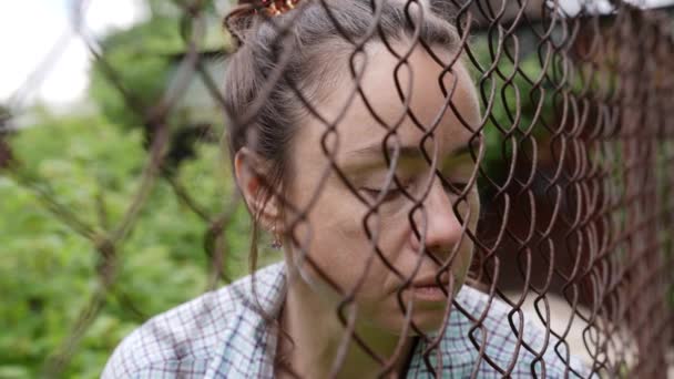 Zbliżenie portret smutnej dorosłej więźniarki za metalowym płotem w miejscach zatrzymania — Wideo stockowe