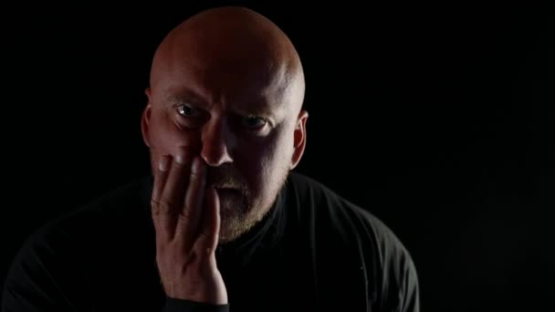 Zblízka portrét plešatého muže stojícího ve tmě, který zažívá velkou duševní bolest — Stock video