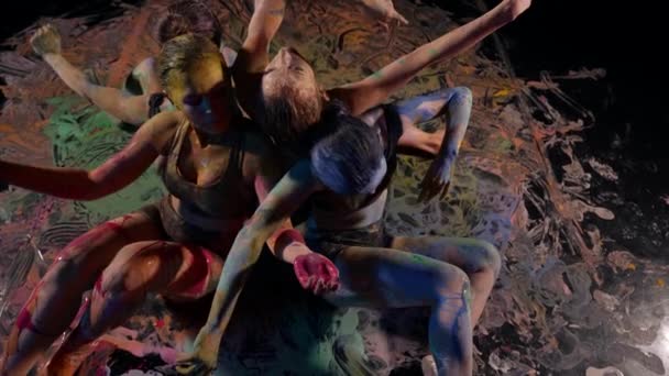 A group of creative elegant female dancers in sportswear improvises in the performance of modern dance, gymnastics and modern dance movements in a black studio paint on their skin — Stock Video