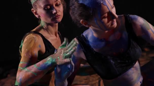 Dos mujeres jóvenes se dedican a una actuación artística con la aplicación de pintura en el cuerpo. Una mujer se dedica al arte de la improvisación, utilizando movimientos corporales — Vídeos de Stock