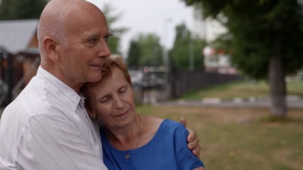 Ένα ερωτευμένο ζευγάρι συνταξιούχων αγκαλιάζονται στο δρόμο κατά τη διάρκεια της ημέρας. — Αρχείο Βίντεο