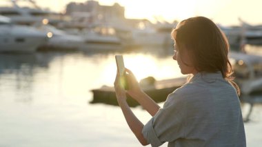 Sosyal medya uygulamasını akıllı telefondan kullanan çekici, yetişkin, zarif bir kadın açık havada kısa mesajlarla haberler aldı.