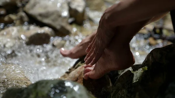 Zblízka žena mytí nohou v čistém horském potoce živá voda pro omlazení Stock Obrázky
