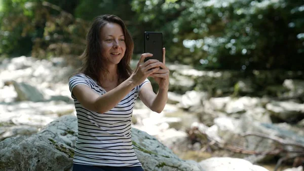 Dospělá žena mluví videokomunikací přes mobilní telefon. Soustředěná hippie žena s chytrým telefonem. Stock Fotografie