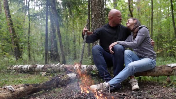 Ένα αγαπημένο ζευγάρι τουριστών σε ένα ταξίδι κάμπινγκ στο δάσος από την αγκαλιά φωτιά και το φιλί — Αρχείο Βίντεο
