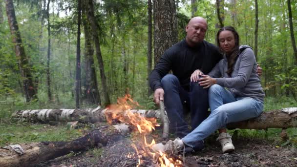 Um casal de turistas em férias uma parada na floresta pelo fogo estão se aquecendo e falando — Vídeo de Stock