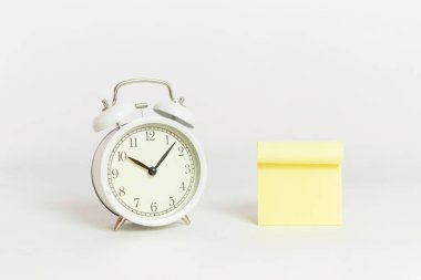 Sarı arkaplanlı beyaz alarm saati beyaz arkaplana iliştirilmiş..