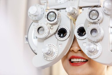 Optik klinikteki Asyalı orta yaşlı kadın göz muayenesini teşhis göz hekimi ile kapatın. Profesyonel göz doktoru, hastanın görüşünü kontrol ediyor. phoropter makinesi, göz bilimi kavramı.