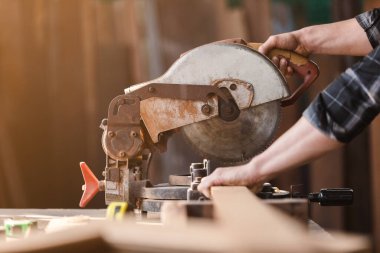 Marangoz koruyucu maske tozu giyer ve odun keserken elektronik testere kullanır. Ahşap fabrikasında zanaatçılık mesleği.