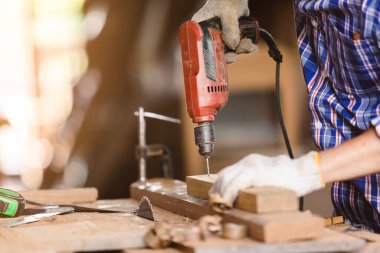 Tahta delmek için elektrikli matkapla çalışan marangoz adam. Kendi ahşap fabrikasında..