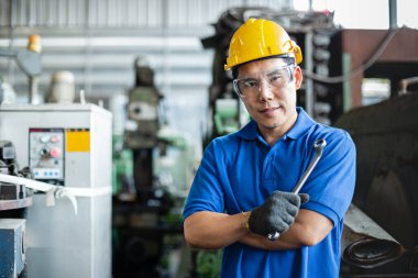Asyalı mühendisler üniforma giyiyorlar ve fabrikada ingiliz anahtarı tutuyorlar. Endüstriyel erkek profesyonel bakım makinesi.