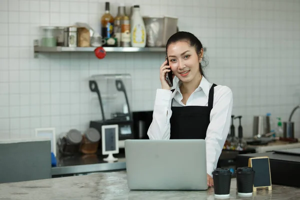 Asiático Jovens Mulheres Barista Desgaste Avental Falando Telefone Usando Computador — Fotografia de Stock