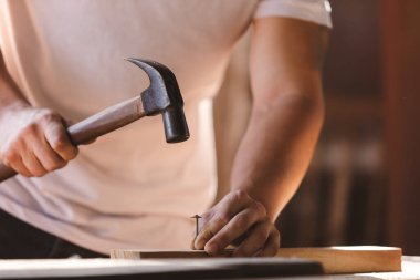 Marangoz kendi çalışma alanında tahtaya çivi çakıyor. Ahşap fabrikasında zanaatçılık mesleği.