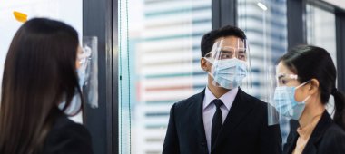 Gizli çekim, tıbbi maske takan ve yüz maskesi takan bir ofis çalışanı, şirkette iş adamları buluşması..