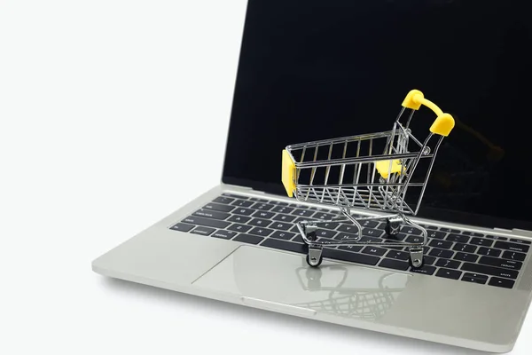 ラップトップコンピュータの白い背景にショッピングカート インターネット上でオンラインスーパーマーケットをショッピング 事業販売はデジタルマーケティングを — ストック写真