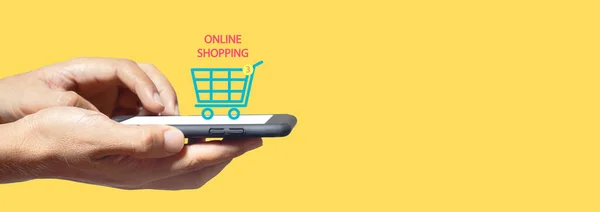 スマートフォンのショッピングをオンラインで手に取り画面上のショッピングカートのアイコン黄色の背景 インターネットで支払いを購入し — ストック写真