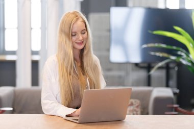 Ofis masasında bilgisayarla bilgisayar kullanan sarı saçlı güzel bir kadın. İş yerinde profesyonel serbest çalışan..
