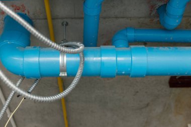 İnşaat alanındaki beton tavanın altındaki mavi PVC su borularının yakın çekimi, tesisat sistemini ve su boşaltma tesisatını gösteriyor. Altyapı ve boru işi sistemi oluşturma kavramı.