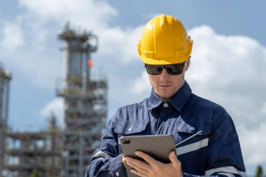 Güvenlik kaskı takan ve sanayi bölgesinde tablet kullanan mühendis, fabrika işletmesini, endüstriyel teknolojiyi, dijital denetimi, bakım planlamasını ve mühendislik veri yönetimini temsil ediyor..