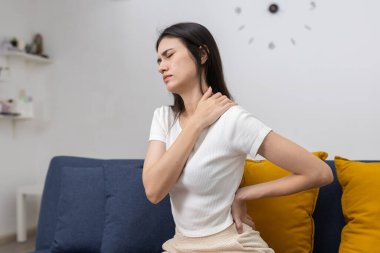 Genç kadınlar kanepede otururken boyun ve bel ağrısı hissediyorlar, muhtemelen kötü duruş, uzun oturma ya da kas zorlanması yüzünden. Ofis sendromu ve günlük rahatsızlık kavramı.