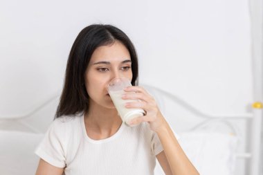 Kadınlar yatak odasında bir bardak süt içerler, sağlıklı yaşam tarzını, kalsiyum alımını ve sabah beslenmesini teşvik ederler. Sağlık kavramı, kişisel bakım günlük sağlık rutini.