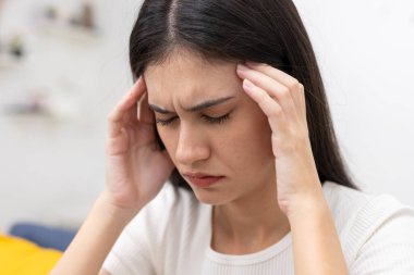 Şakaklarına acı ifadesiyle dokunan, baş ağrısı ya da migren belirtileri gösteren kadınların kapatılması, sağlık, stres, ağrı kesici veya tıbbi durum içeriği için mükemmel.