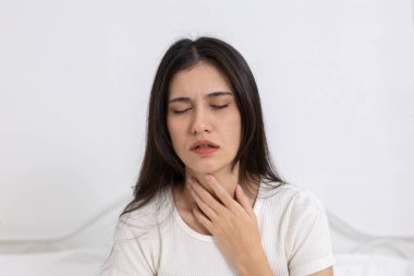 Boğazı ağrıyan, bademcik iltihabı olan, solunum yolu enfeksiyonu olan kadınlar boğazına dokunuyor. Soğuk algınlığı, grip veya viral hastalık kavramı.