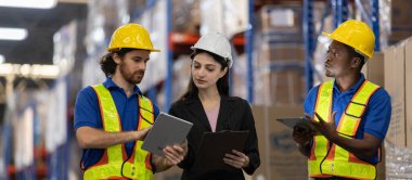 Depo çalışanları ve kadın denetçi envanter yönetimini tartışmak için dijital tablet ve pano kullanıyor. Modern lojistik ve tedarik zinciri operasyonlarında takım işbirliği kavramı.