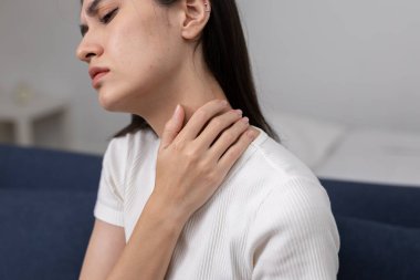 Boyun ağrısından muzdarip kadınlar, iki eliyle boynunu tutuyorlar ve rahatsızlık içinde gözlerini kapatıyorlar. Evde kas gerilimi, stres, yorgunluk, sağlık hizmetleri kavramı.