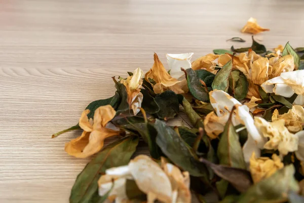 Dry flowers leaves on wooden table top view. Colorful herbs tea flat lay.