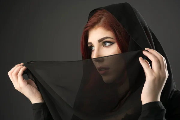 Young muslim woman covering her face and hair with a black veil — Stock Photo, Image