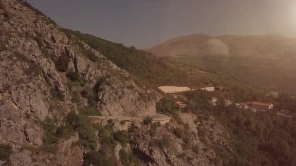 Aérea de las serpentinas montañas con un convertible en tiempo soleado al atardecer viaje — Vídeos de Stock