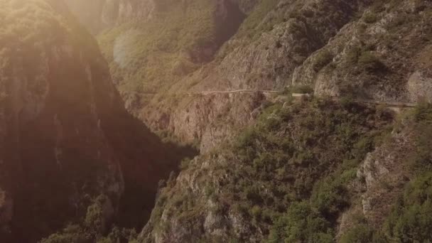 Aérea de las serpentinas montañas con un convertible en tiempo soleado al atardecer viaje — Vídeos de Stock