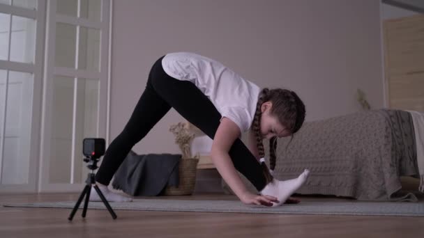 Девочка-ребенок транслирует онлайн-курс и пишет блог о гимнастике дома — стоковое видео