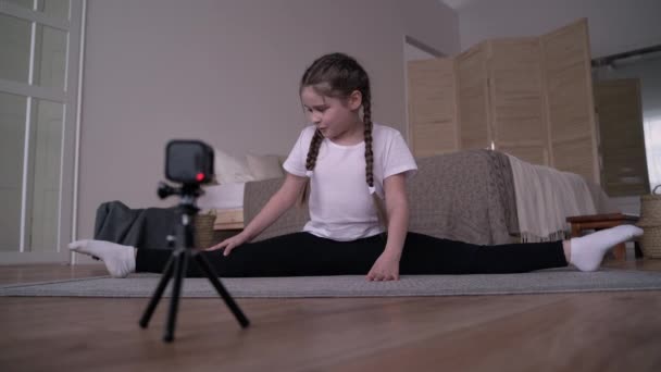 Flicka barn sänder en online-kurs och skriver en vlog om gymnastik hemma — Stockvideo