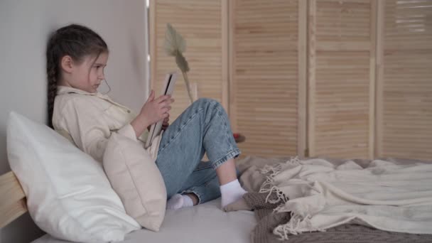 Menina jogando um jogo no tablet móvel. se divertindo em férias em casa — Vídeo de Stock