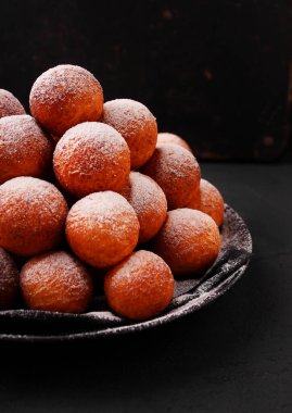 Koyu bir arka planda pudra şekerli kızarmış donutlar, üst manzara. Şişman Perşembe, Polonya bayramı