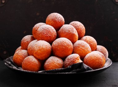 Koyu bir arka planda pudra şekerli kızarmış donutlar, üst manzara. Şişman Perşembe, Polonya bayramı