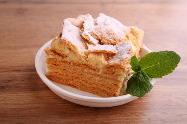 Napolyon pastası naneyle süslenmiş, kırsal bir arka planda bir tabakta