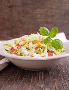 Tahıllı lahana salatası mısır ve yengeç çubukları eski bir arka planda bir tabakta.