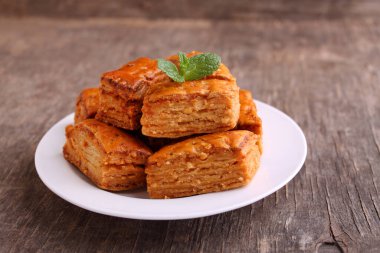 Baklava, geleneksel Türk tatlısı. Beyaz tabakta gevrek baklava, eski ahşap arka planda..