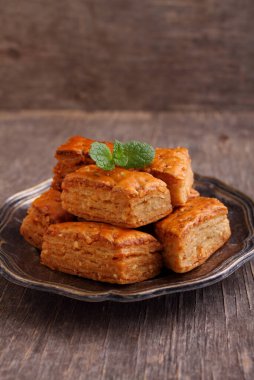 Baklava, geleneksel Türk tatlısı. Nane şekeriyle süslenmiş eski ahşap arka planda gevrek bir baklava..