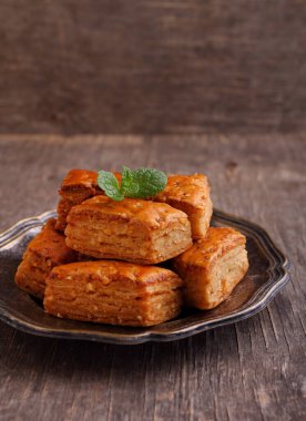 Baklava, geleneksel Türk tatlısı. Nane şekeriyle süslenmiş eski ahşap arka planda gevrek bir baklava..